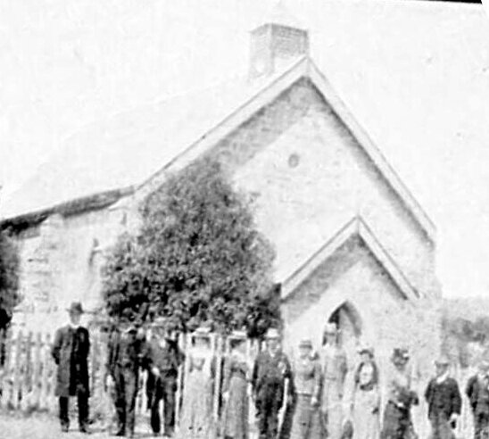 A group of people standing in front of the stone church in Mittagong, about 1905